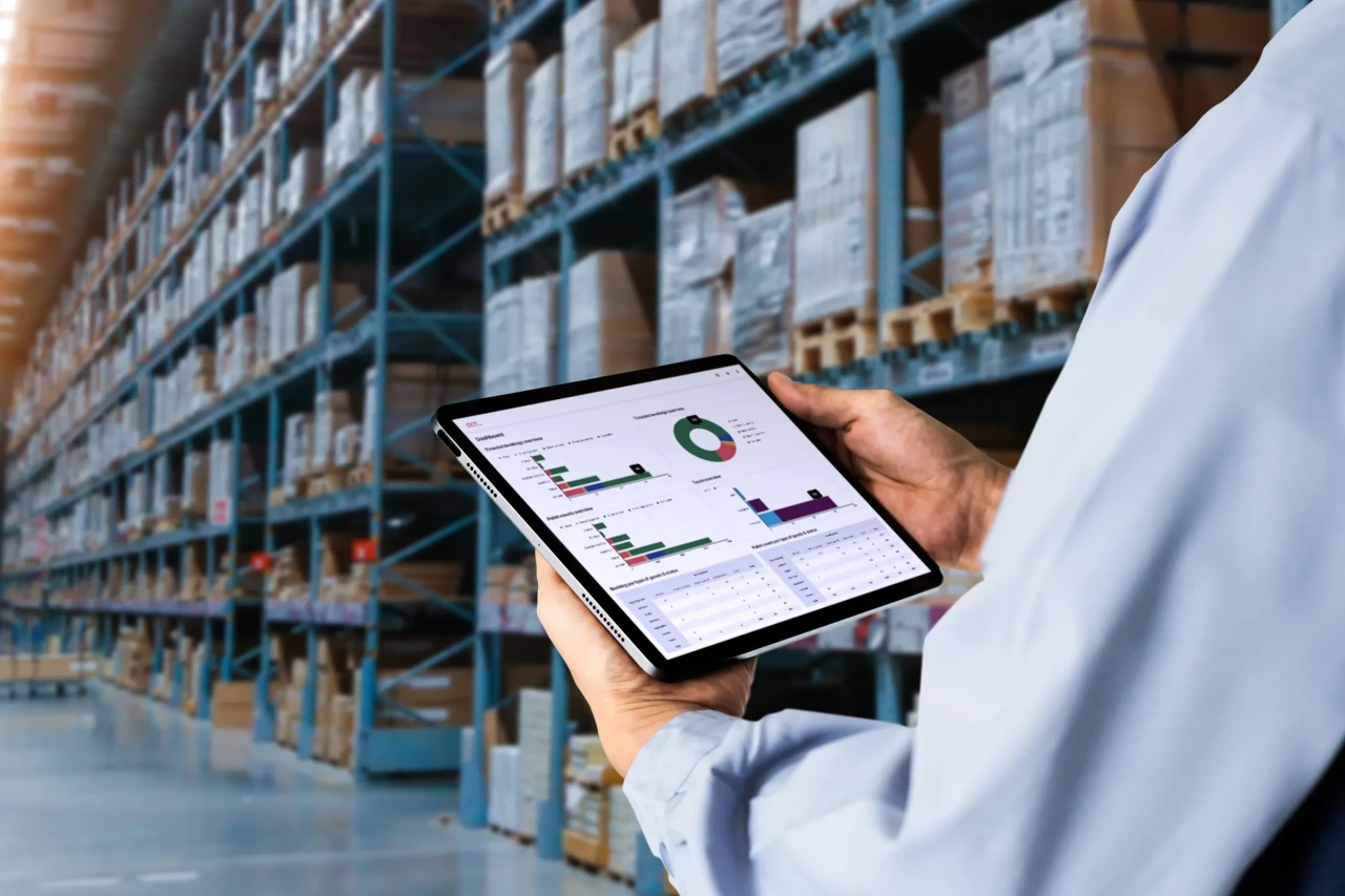 Manager using digital tablet,showing warehouse software management dashboard on blurred warehouse as background.