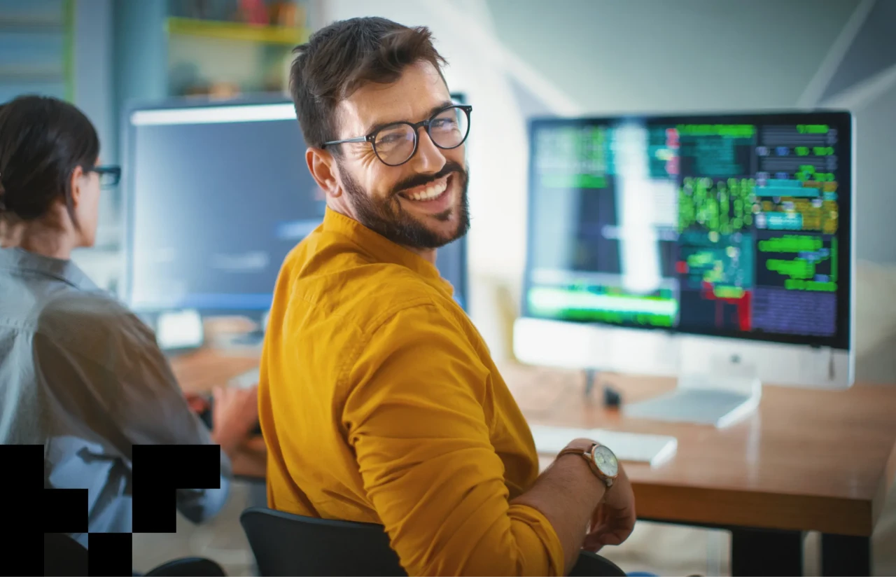 Closeup over the shoulder view of a software developer smiling to the camera.