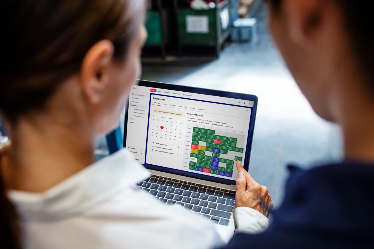 two individuals looking at a laptop screen displaying a booking and time slot management interface.